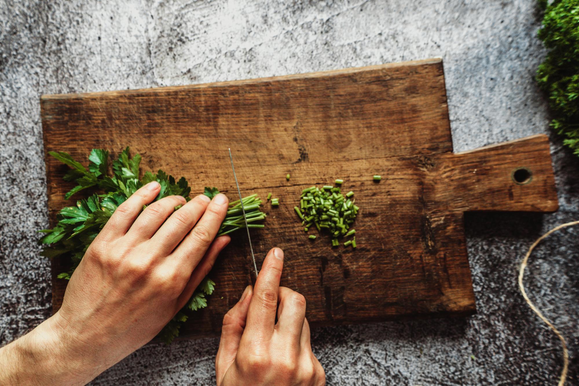 Mani che tagliano erbe fresche